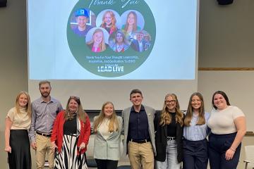 The panel members from the LEADLive event pose for a photo in front of a LEADLive slide 