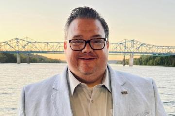 Portrait of man in suit jacket with glasses with bridge in background
