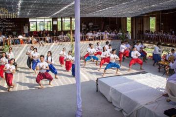 Thai Moradokmai Theatre dancers are shown dancing in a large group