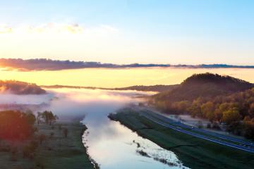 An aerial image of the Hocking River and the highway and surrounding countryside with fog in the air on a spring morning