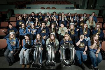 Staff members are shown in the seats at the Athena Cinema holding the numbers 1-1-0 and wearing party hats and blowing party horns