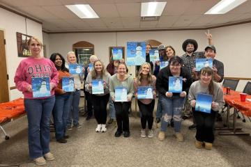 Group of people holding up paintings