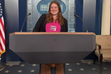 Abby Waechter stands behind a podium in a White House press room