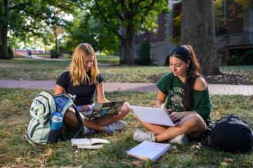 OHIO students work on projects on their laptop computers while sitting on the College Green on a warm day