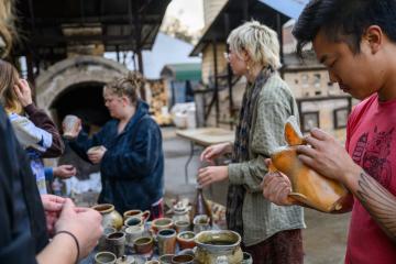 shoppers peruse ceramic pieces made by Ohio University students and faculty in an outdoor kiln yard
