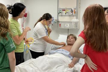 a student practices listening for a heartbeat in a nursing lab