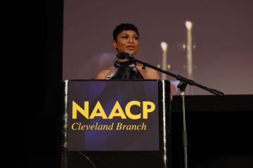 journalist Jericka Duncan stands on stage behind a podium with the NAACP Cleveland Chapter logo