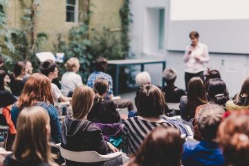 A professor teaches while standing in front of a class of students