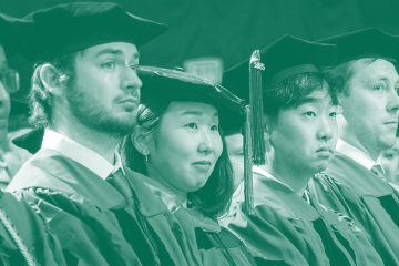 A group of faculty in academic regalia sit in a row