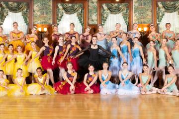 Approximately 50 young ballet dancers in full brightly colored costumes smiling