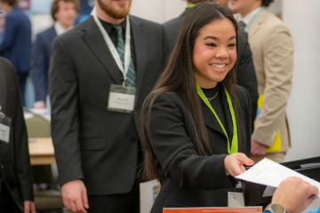 An OHIO student hands a resume to a company representative at a Career Fair at OHIO