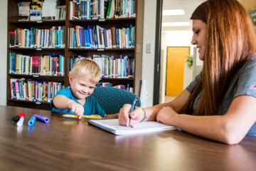 An adult works with a student during a counseling or social work session at a school