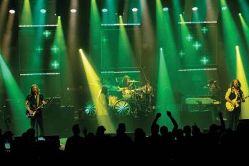  members of the band My Morning Jacket perform on stage surrounded by green and yellow lighting