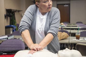 woman performs cpr on dummy