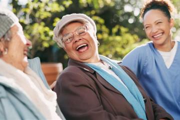 A community health worker sits and talks with two individuals