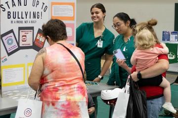 two nursing students talk share information on stopping bullying at a health fair