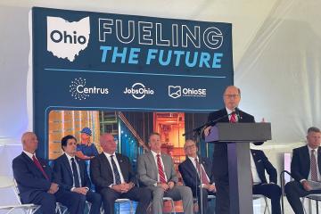 A speaker stands at a podium in front of local and state leaders and in front of a sign that says Ohio - Fueling The Future - Centrus, JobsOhio and OhioSE Economic Development