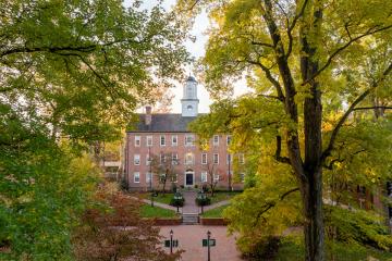 Cutler Hall is surrounded by colorful trees on the College Green on a day in fall
