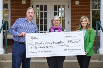 Matthew Roberts, Jennifer Bowman and Melissa Clark hold a poster of a check for $50,000