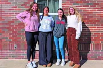 Four female students standing outside of a brick building