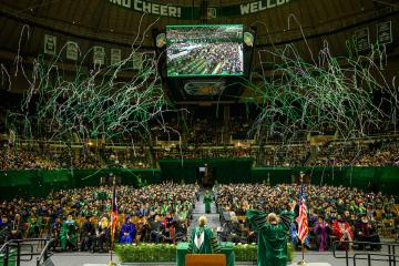 Green and white streamers explode over the 2025 fall Commencement ceremony