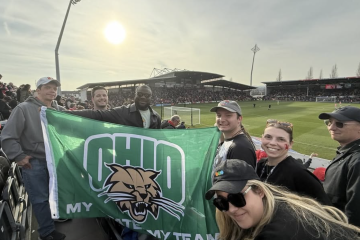OHIO alumni and staff hold an Ohio University flag while at Wrexham Football Club game 