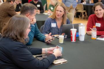 OHIO faculty and staff talk with one another while sitting at tables at the T1 Summit