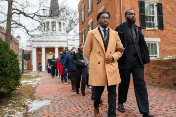 a group marches arm-in-arm across College Green