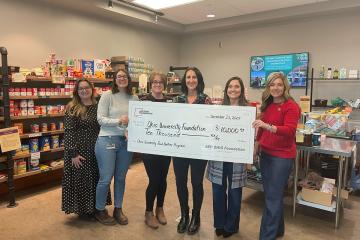 Representatives of Ohio University and the AEP Ohio Foundation hold a giant check while standing in a food pantry