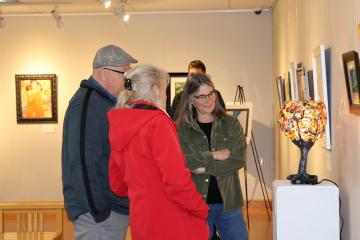 Three people look at a hand-crafted lamp in the art gallery at OHIO Chillicothe