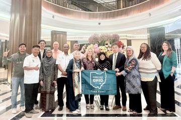 OHIO representatives and OHIO alumni hold a flag that says Forever OHIO - Proud Alumni while they are at an event in Kuala Lumpur, Malaysia