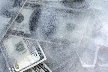 100 dollar bills frozen under a sheet of ice.