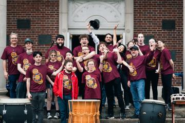The Ohio U Percussion club standing together with large taiko drums in front of them. 