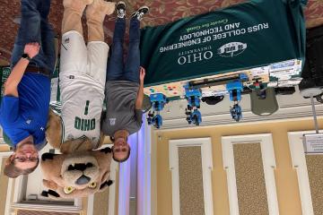 Brandon Petrie standing with Rufus at an outreach event with robots.