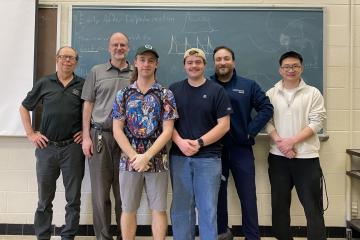 OHIO students, faculty and staff who work with the OSC stand together in front  of a chalkboard in an OHIO classroom