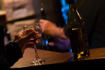 Wine glass and bottle sit on table