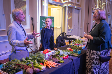 people talking at produce table at environmental impact event 