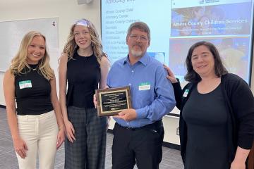 Shawn Stover stands with Ohio University representatives while he holds his Outstanding Community Partner Award