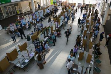 An ovehead image of people standing next to three long rows of exhibits at the Regional Science Day event at Ohio University