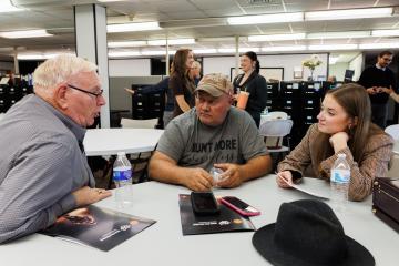 Emily Stokes sits at a table and discusses a project with members of the Mayors Partnership for Progress