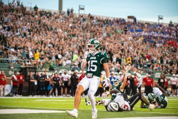 An OHIO Football player celebrates in the end zone in front of a large crowd  in Peden Stadium