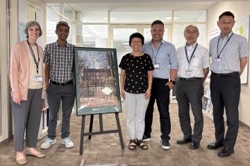 OHIO and Chubu University representatives stand together next to artwork that features OHIO's Cutler Hall