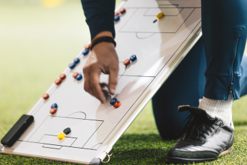coach kneeling showing plays on a whiteboard