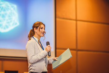 woman standing in front of room with a microphone