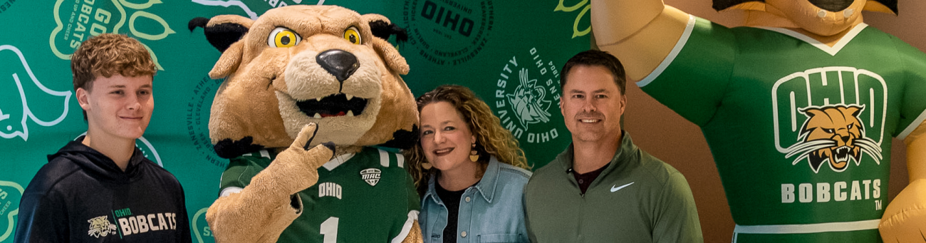 a family posing for a photo with Rufus the Bobcat