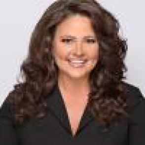 Headshot of Vicki King-Maple. Caucasian women with long brown curly hair wearing black jacket. 