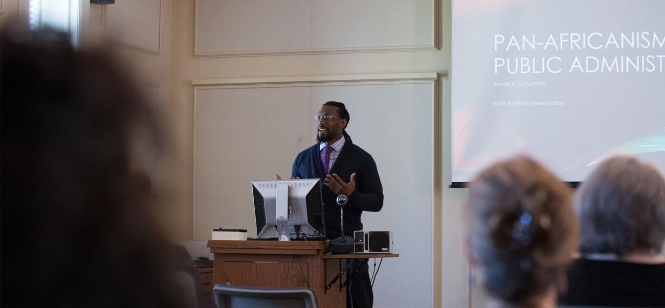 Man at podium in front of screen showing public administration class lecture