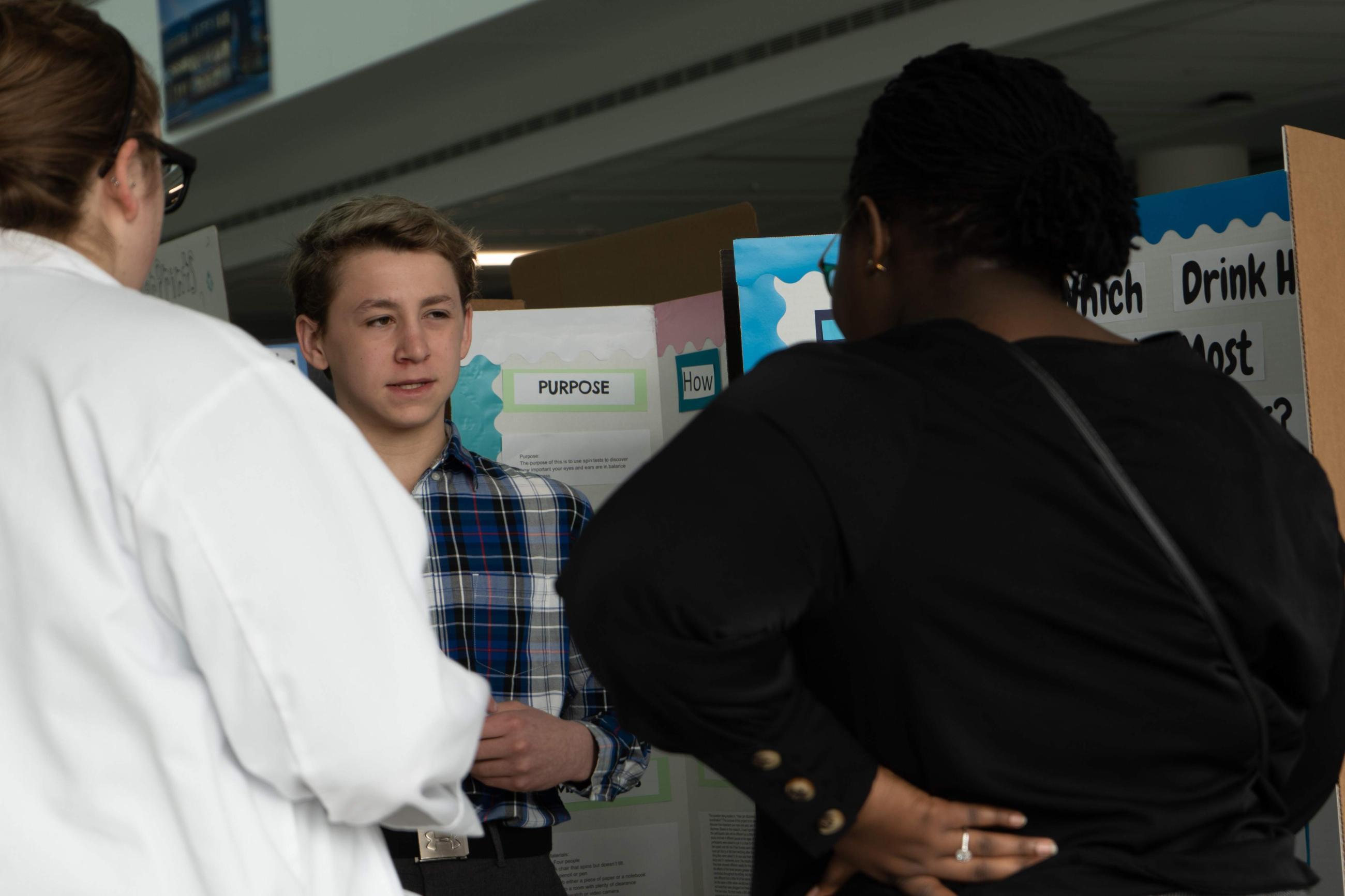 Student explaining their science display to attendees