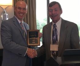 Jason Jolley shaking another person's hand holding award